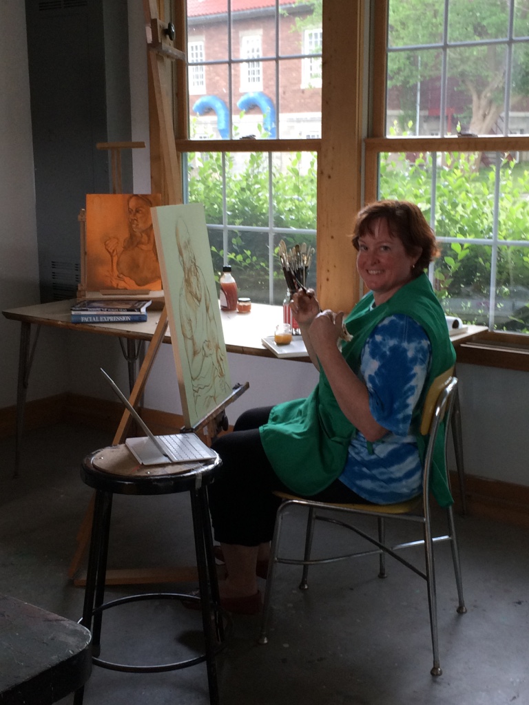 Artist sitting in front of her easel painting with a paint brush in her hand. 