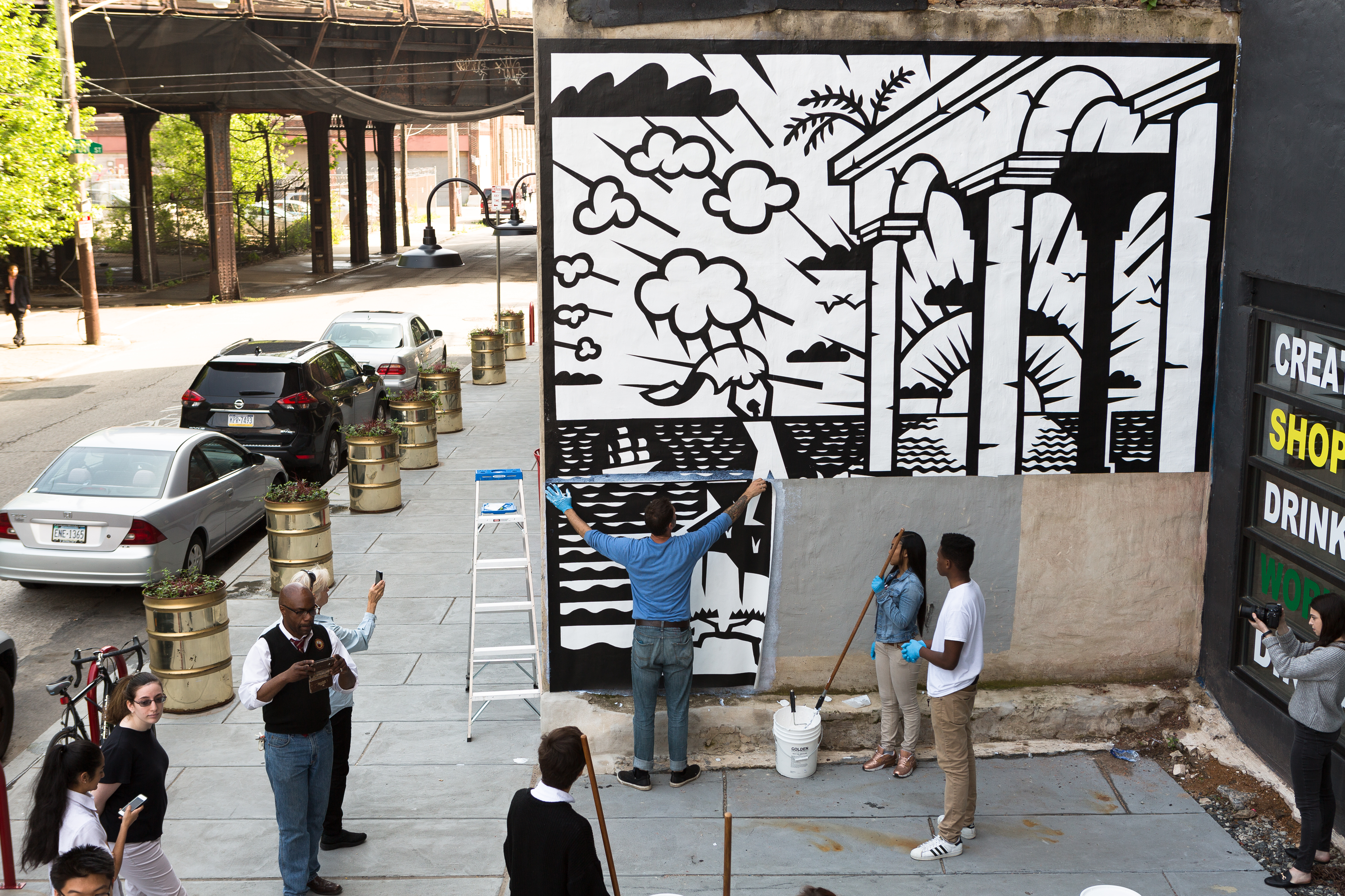 People install a panel of a large black and white mural in Philadelphia