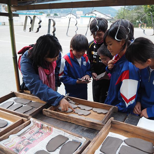 Children in Japan look inside a kiosk where clay cut-outs are laid out