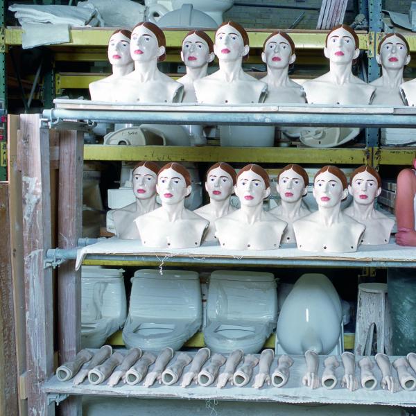Woman standing with a bunch of ceramic renditions of her. 