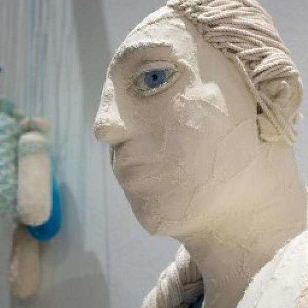 A white bust of a woman with one giant blue eye