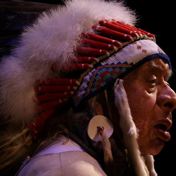 Native man wearing a white headdress in profile
