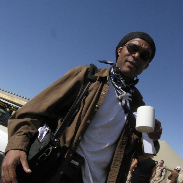 Man wearing sunglasses outside holding coffee cup.