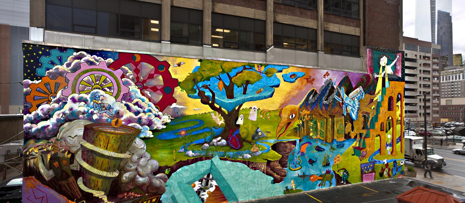 Colorful mural on side of building facing a parking lot.