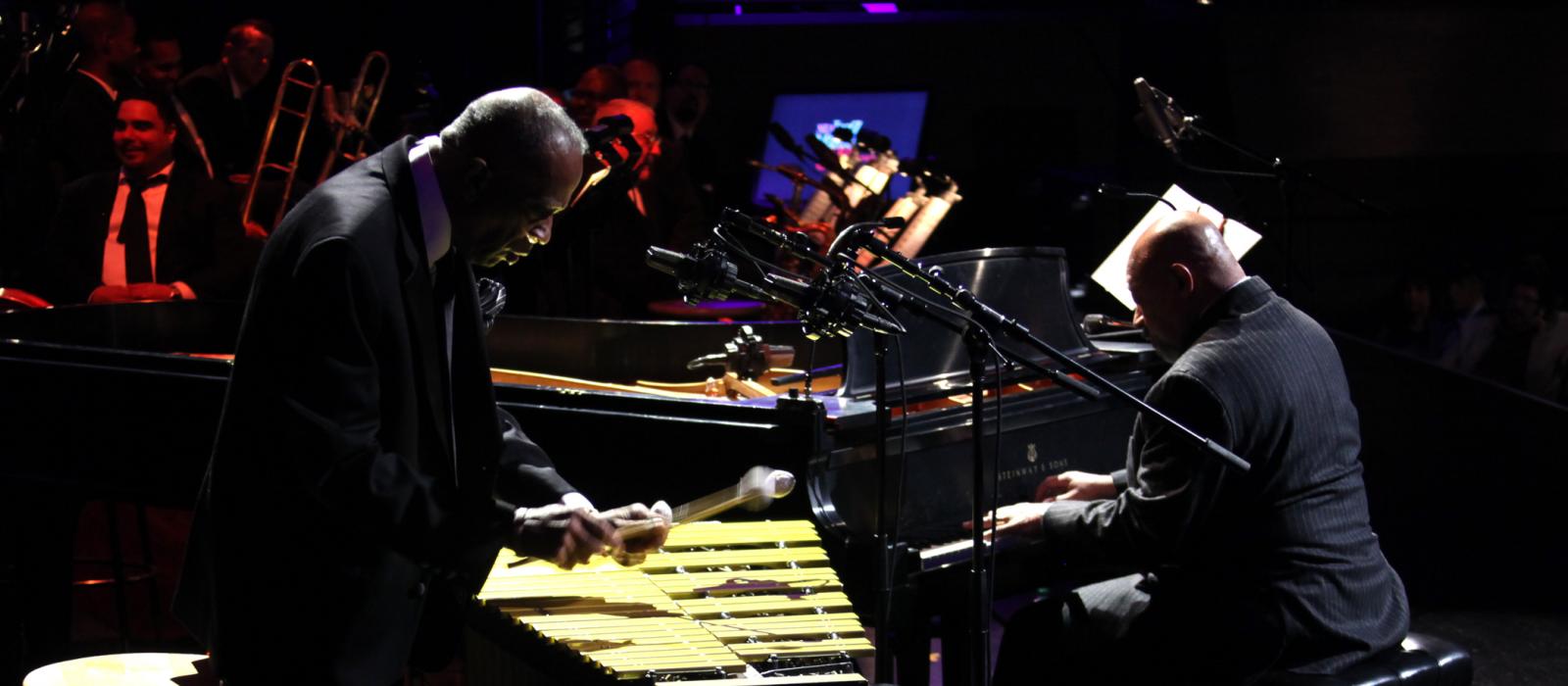 Man playing vibes and man playing piano on stage.
