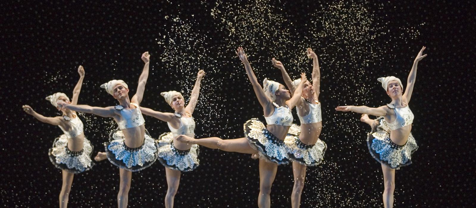 Dancers in tutus on stage standing on pointe.