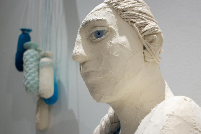 A white bust of a woman with one giant blue eye