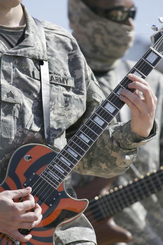 Male in uniform playing a guitar.