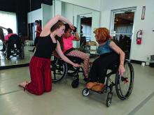 A woman in a wheelchair gives instructions to two younger dancers, one of whom is also in a wheelchair