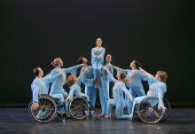 an ensemble of dancers some of whom are in wheelchairs performing on stage