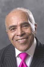 Headshot of a man in a suit and pink tie