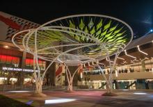 a two-story tree-like sculpture with a series of white trunks holding up a canopy of attached leaf like translucent shapes
