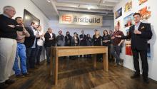 A group of people standing around a newly build table. 