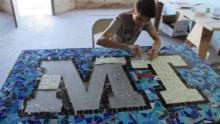 Boy at a table assembling a mosaic with the letters MT.