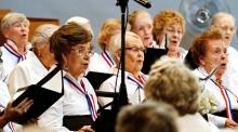 A group of older adult women singing in a chorus