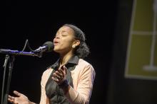 a young black woman is speaking emotively into a microphone 