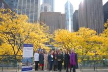 a group of people pose for a photo against a background of trees with yellow leaves
