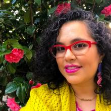 a middle-aged Chicana woman with red glasses and pink lipstick