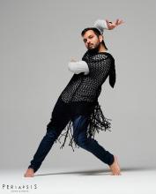 Rohan Bhargava dancing in jeans, a white long-sleeve shirt, and a fringed open knit sweater.