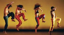 Three male and one felamle dancers high-stepping left to right