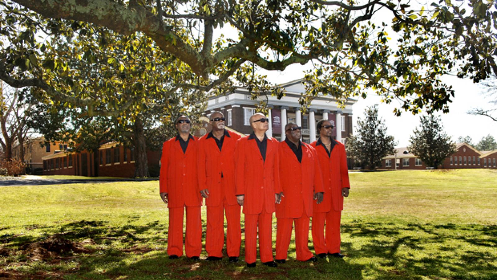 Five men wearing red suits stand outside wearing sunglasses