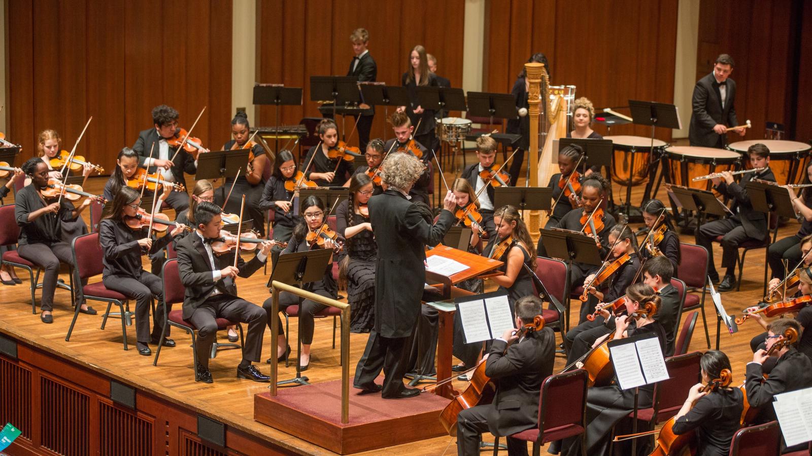 A student orchestra performs on a stage