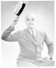 Man seated holding a straw hat in his hand. 