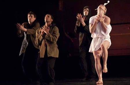 Four dancers with hands uplifted to their chests, three in dress jackets and pants, one in a nightgown