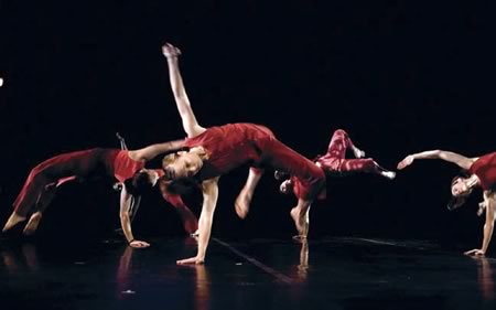 Four women dancers on stage in one-arm back bridge position 