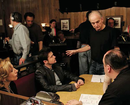David Chase (standing, center) discussing the final scene of The Sopranos with the actors (seated, from left) Edie Falco, Robert Iler, and James Gandolfini. Photo by Will Hart/HBO