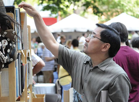 A man in glasses browsing shelves of books at Printers Row Lit Fest