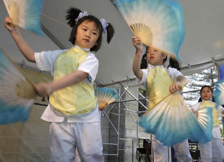  two young girls in festive costume dancing with multi-colored fans