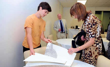  student showing work on large paper to two adults