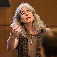  A woman stands beside a podium gesturing to the audience.