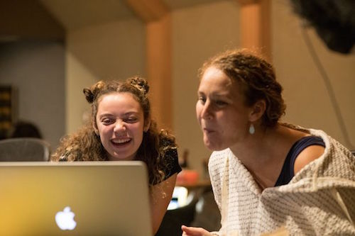 two women, one younger, one older, sit in front of an open laptop