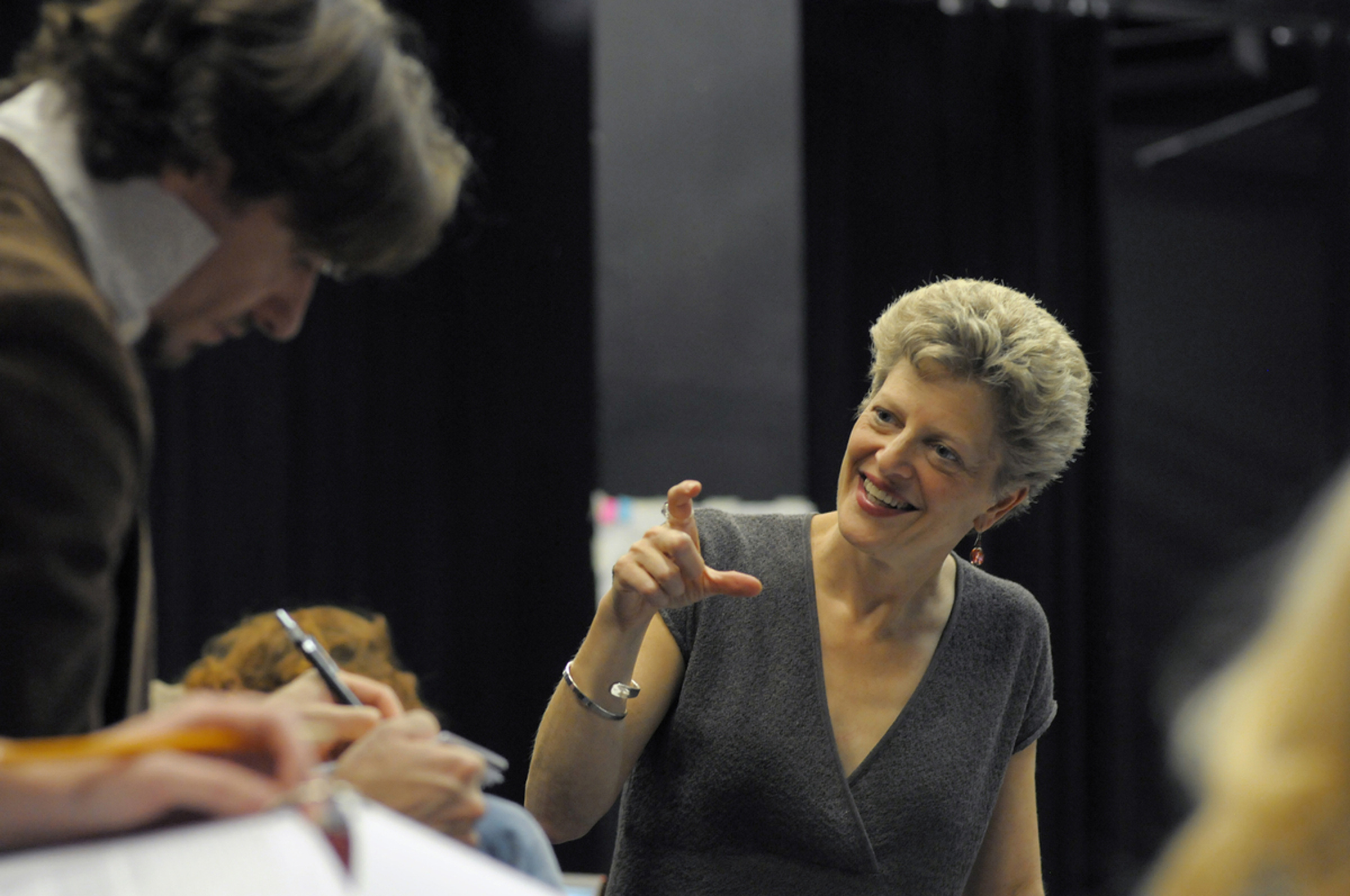 Woman gesturing to actors on stage. 