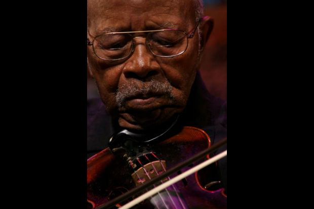 Close up facial shot of man as he plays fiddle