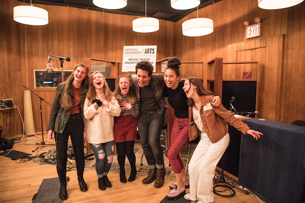 A group of young people pose for the camera inside a recording studio.