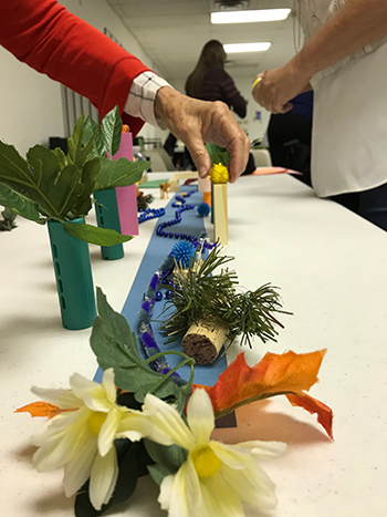 People's hands toy with arts and crafts objects on a long table