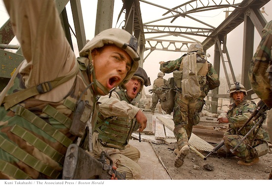 soldiers in combat fatigues fighting their way across a bridge