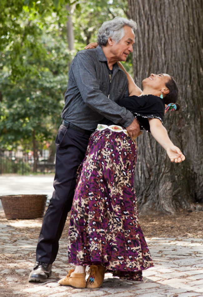 An older man dipping a smiling older woman