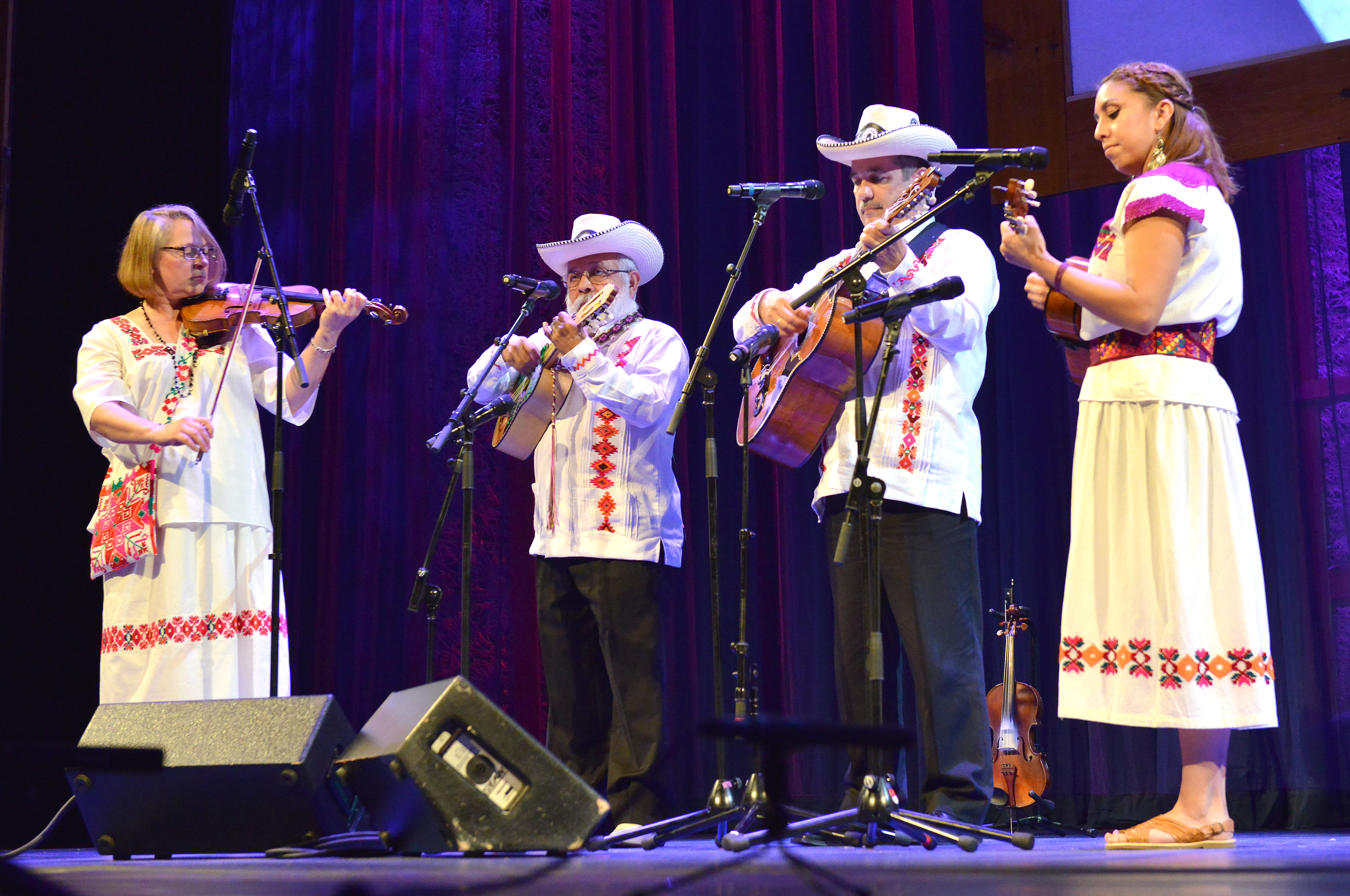 Four band members playing various instruments wearing traditional Mexican attire.