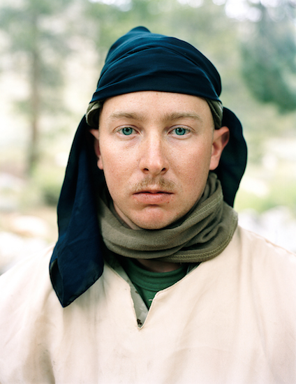 a man with blonde hair and blue eyes wears a Taliban-like costume