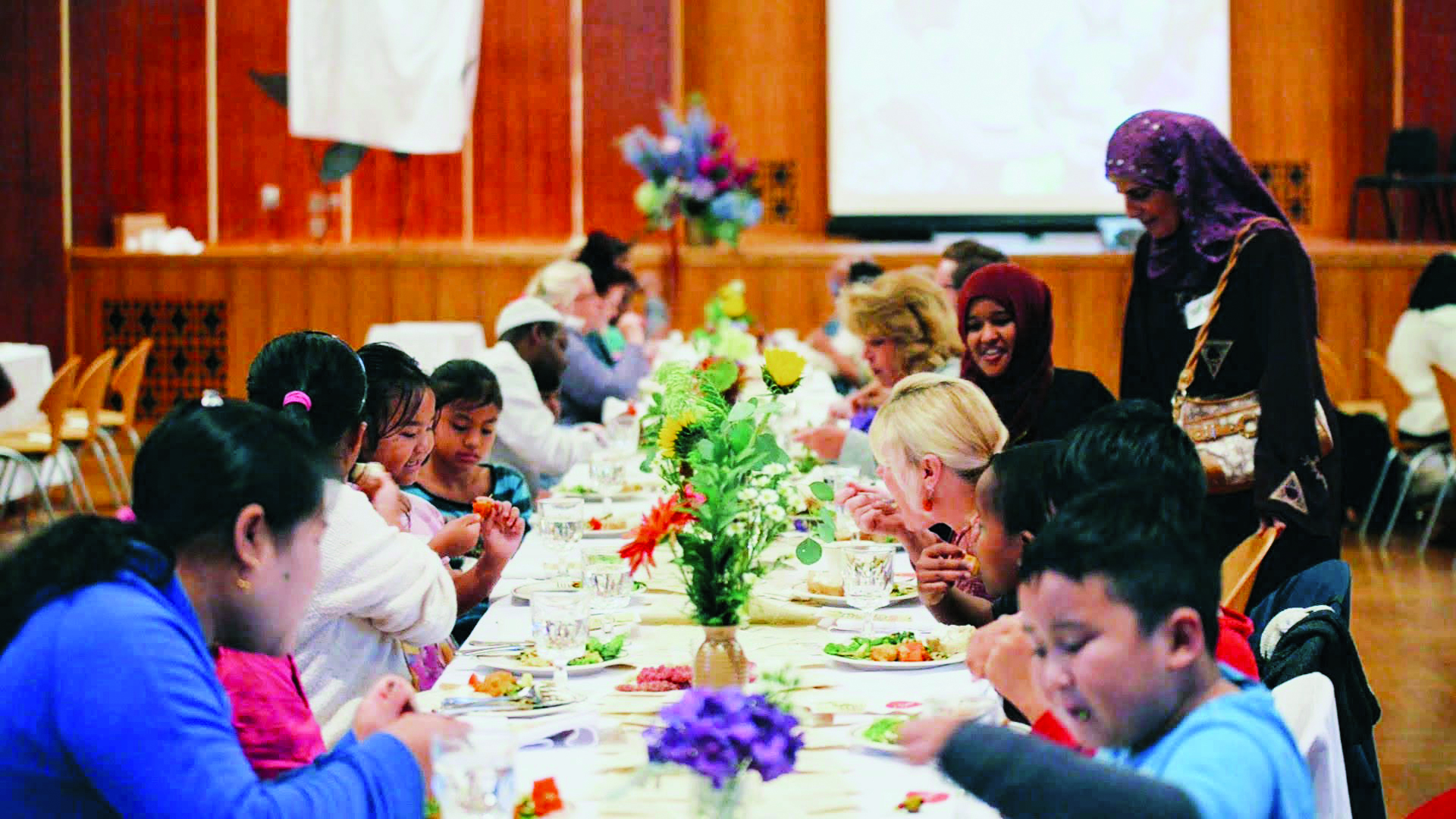 Children sit at a long table and eat