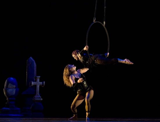 A male and female dancer performing on stage with an apparatus. 