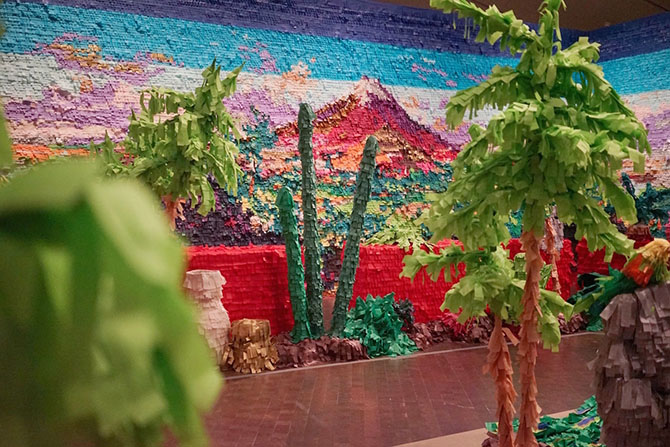 Desert landscape with cacti made entirely out of paper fringe sits in a museum space
