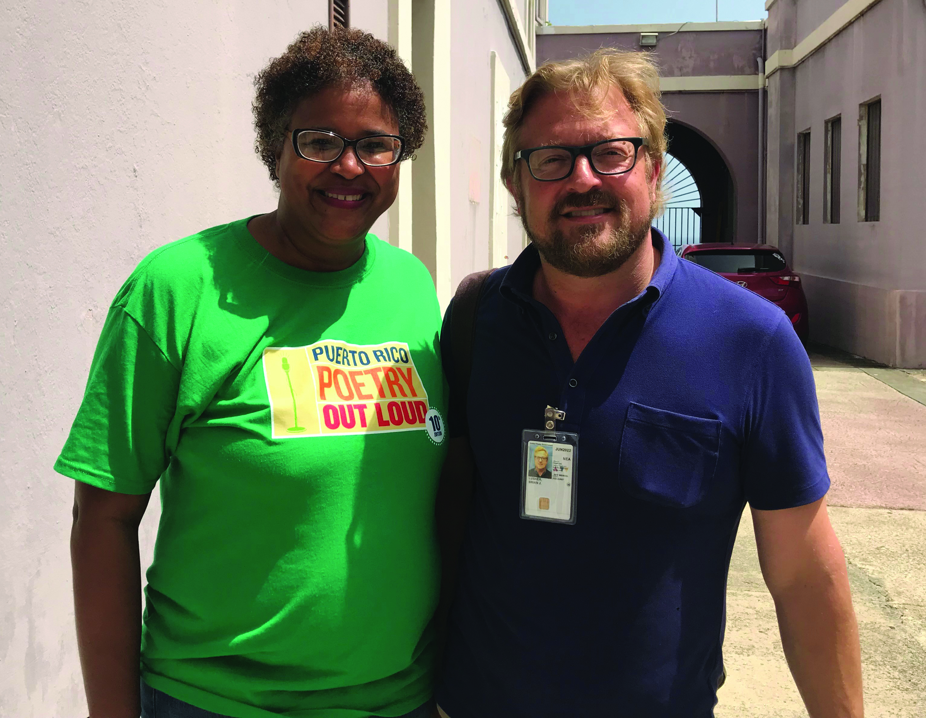 A man and woman stand together smiling at camera