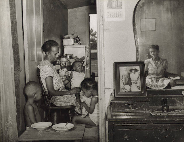 Ella Watson with three young children and a young woman in a crowded apartment