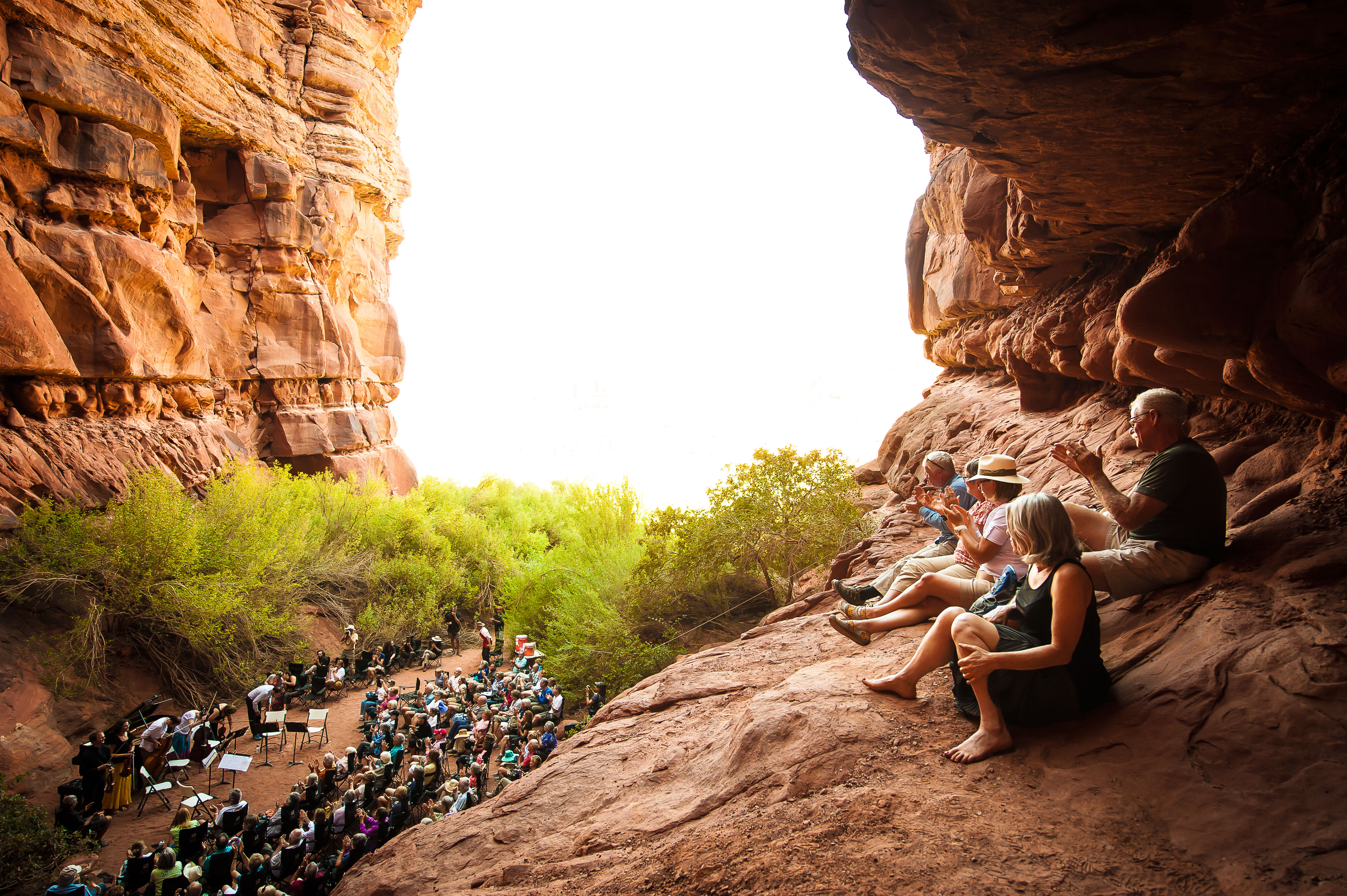 Festival goers sitting on top of the red rocks watching a performance.