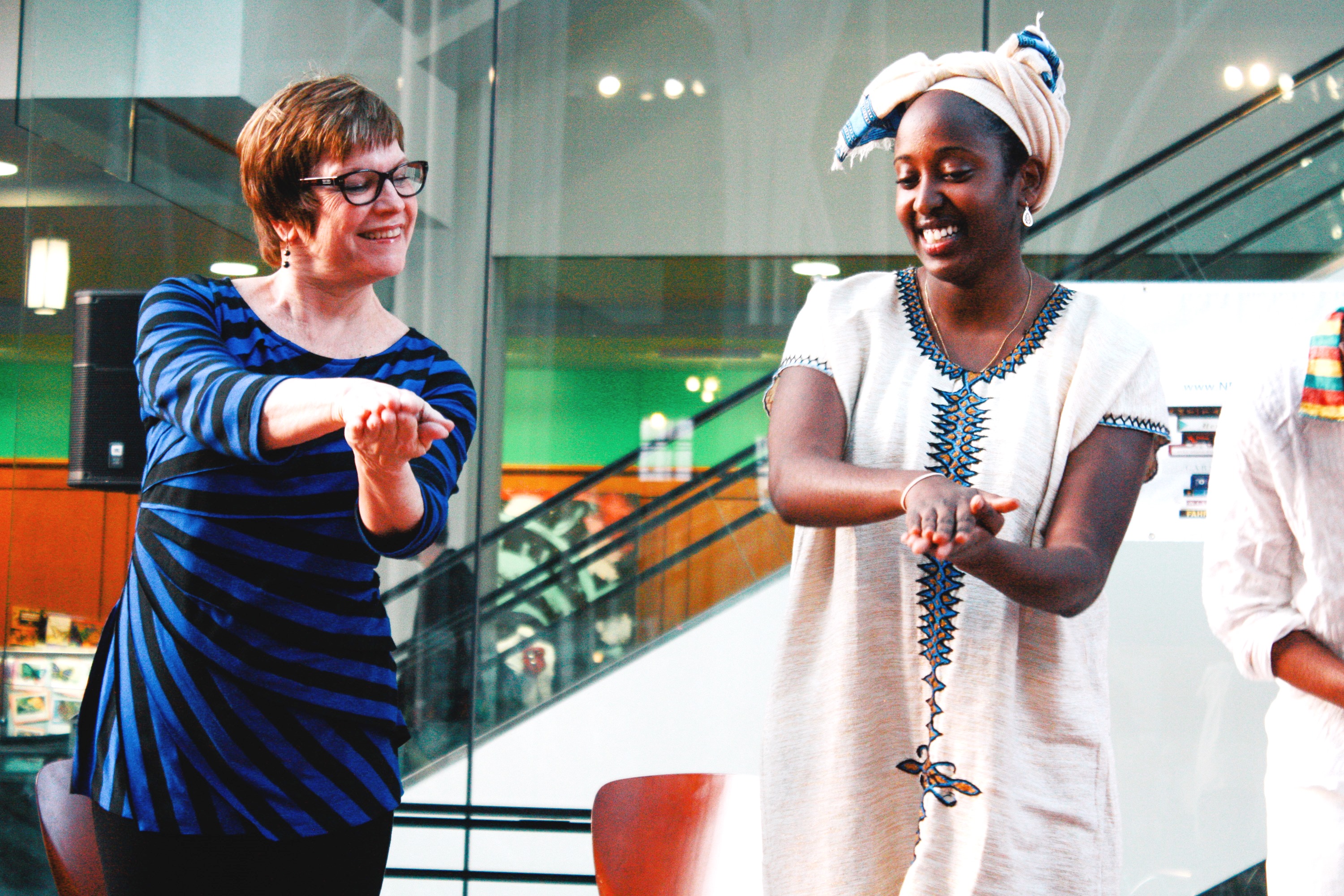 A woman practicing traditional Ethiopian dance with an Ethiopian native. 